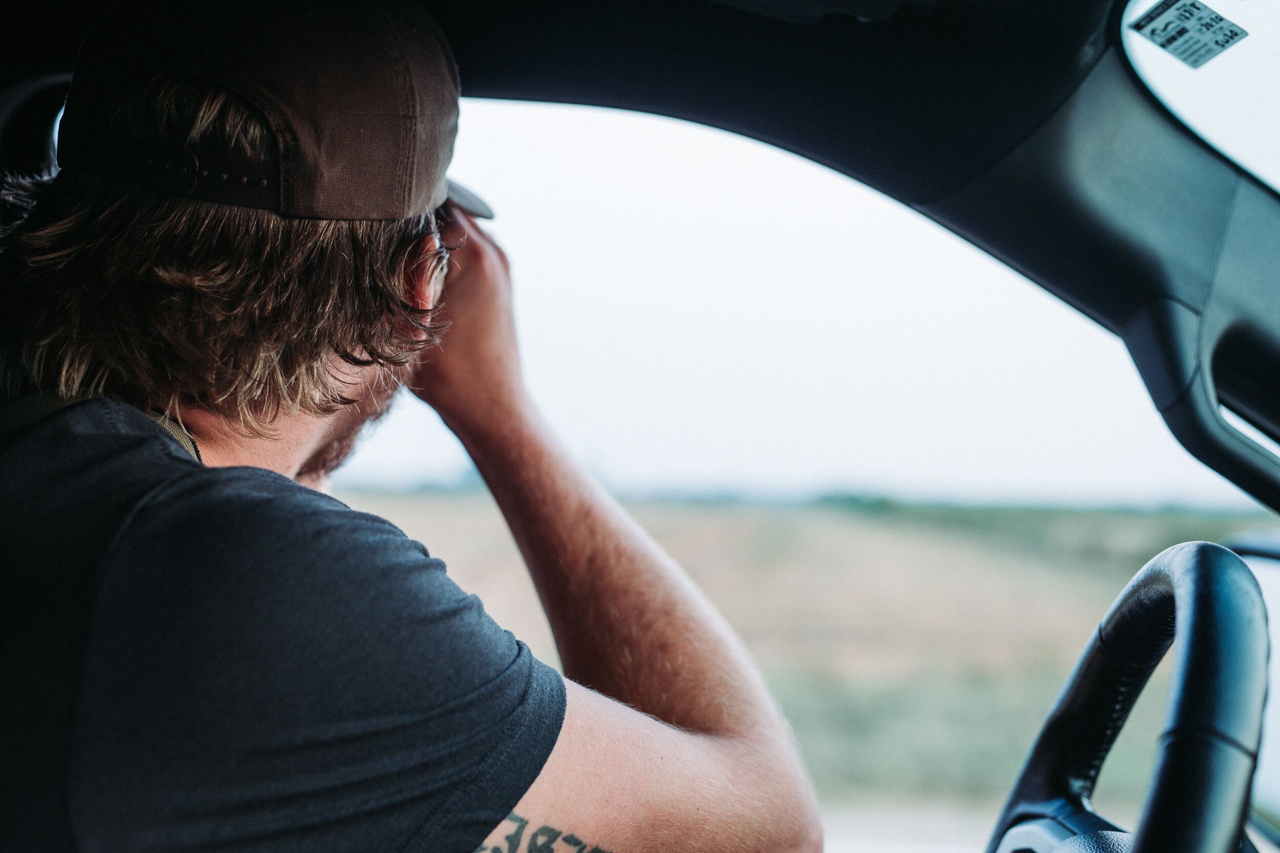 A turkey hunter scouts a field using binoculars from a vehicle. 